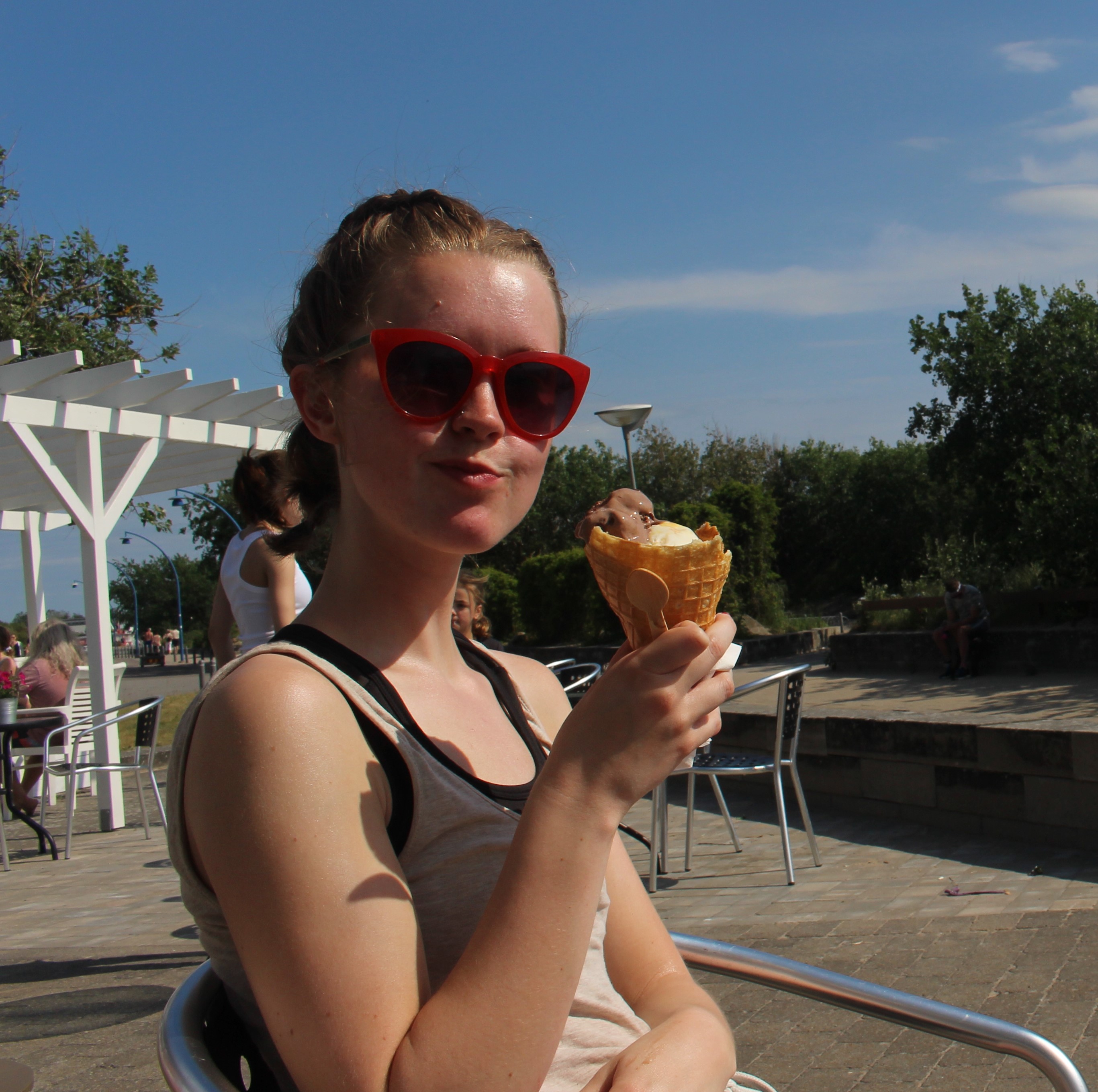 En bild på Kajsa med en glass i sommarsolen.